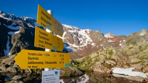 Wegweiser Staubaier-Höhenweg Wegweiser Staubaier-Höhenweg mit Bergsee im Hintergrund