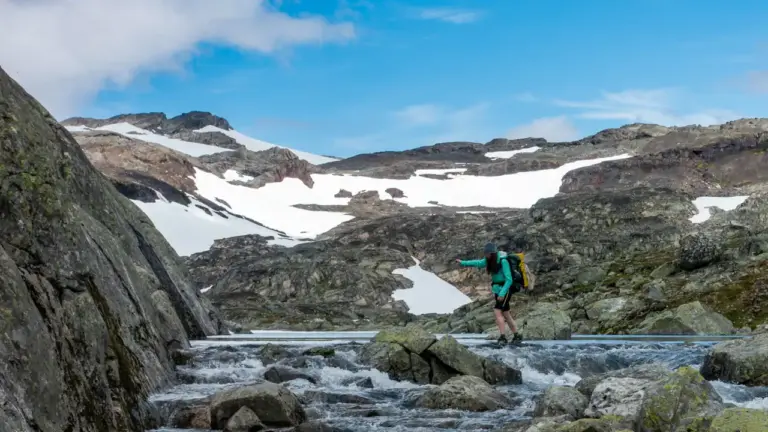 Gefährliche Flussquerung beim Trekking auf Steinen balancierende Wandering beim Furten - geschlossene Rucksackgrute, keine Trekkingstöcke