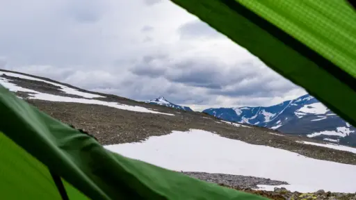 lick nach Nordwesten über den Tjønnholtjønne zum Høgdebrotet Blick aus einem grünen Zelt nach einer Regennacht Richtung Nordwesten auf die wolkenverhangenen Gipfel des Høgdebrotet oberhalb des Sees Tjønnholtjønne in Jotunheimen.