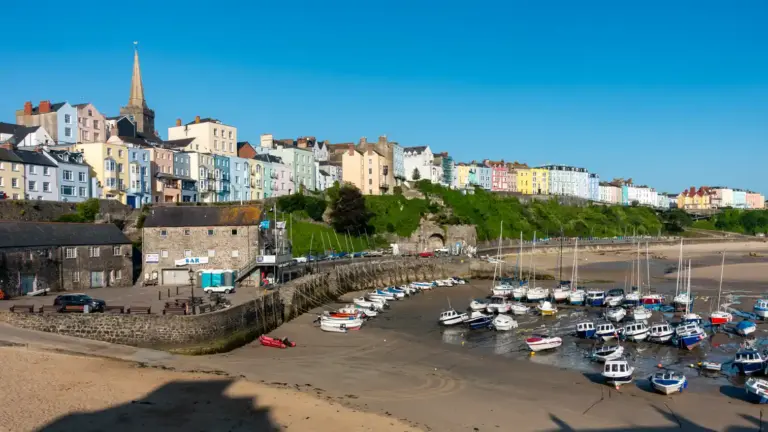 Stadtpromenade von Tenby mit Hafen Tenby: Häuser der Stadtpromenade mit Blick auf den Hafen bei Ebbe (viele kleine Boote auf Grund)