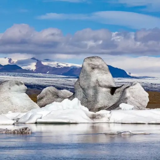 Eisberge in der Fjallsárlón Gletscherlagune Große, mit schwarzer Vulkanasche durchsetzte Eisberge in der Fjallsárlón Lagune vor der Kulisse des Öræfajökull.