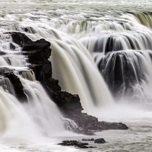 Detailaufnahme der Kaskaden des Gullfoss Wasserfalls Langzeitbelichtung der fließenden Wasserkaskaden des Gullfoss Wasserfalls über dunkle Basaltstufen.