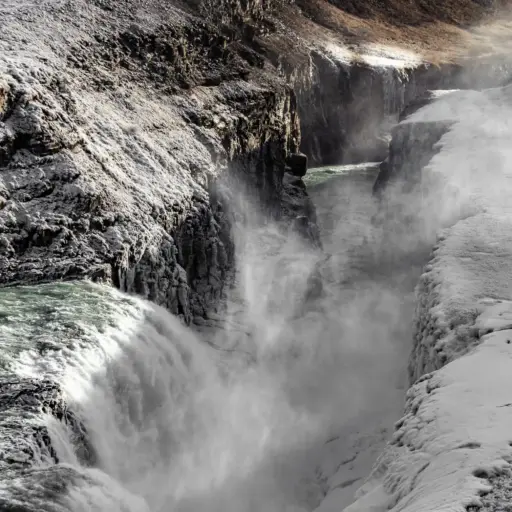 Die tiefe Schlucht des Gullfoss im Winter Blick in die tiefe Schlucht des Gullfoss Wasserfalls mit aufsteigender Gischt und schnee- sowie eisbedeckten Felswänden.