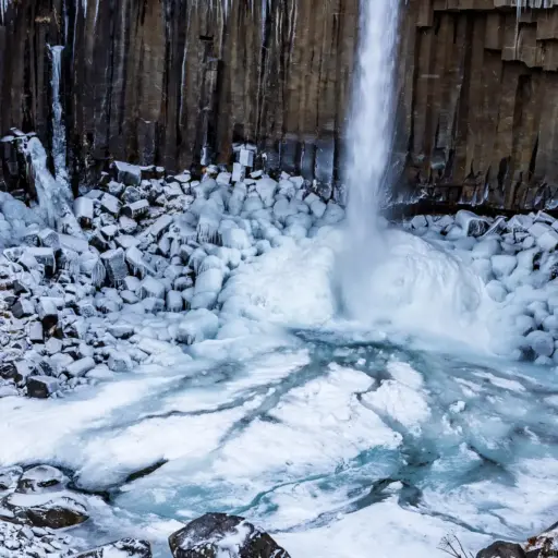 Svartifoss Wasserfall – Islands markante Basaltsäulen Nahaufnahme des Svartifoss Wasserfall mit markanten dunklen Basaltsäulen, umgeben von Schnee und gefrorenem Eis.