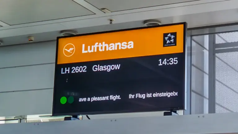 Boarding-Screen für den Flug München - Glasgow Eine orange-schwarze Flughafen-Anzeigetafel der Lufthansa zeigt den Flug LH 2602 nach Glasgow mit der Uhrzeit 14:35 Uhr und der Nachricht Ihr Flug ist einsteigebereit.