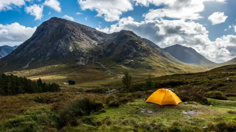 Trekking und Wildcamping am Buachaille Etive Mòr, West Highland Way Ein gelbes Trekkingzelt auf einer grünen Wiese vor der Kulisse des Berges Buachaille Etive Mòr in den schottischen Highlands am West Highland Way.