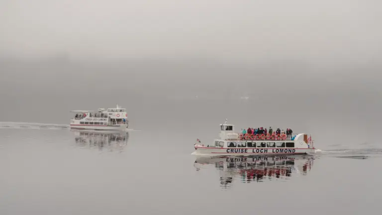 Personenboote von Cruise Loch Lomond am Rowardennan Hotel, West Highland Way Zwei weiße Ausflugsschiffe mit der Aufschrift Cruise Loch Lomond fahren bei dichtem Nebel über das spiegelglatte Wasser von Loch Lomond.